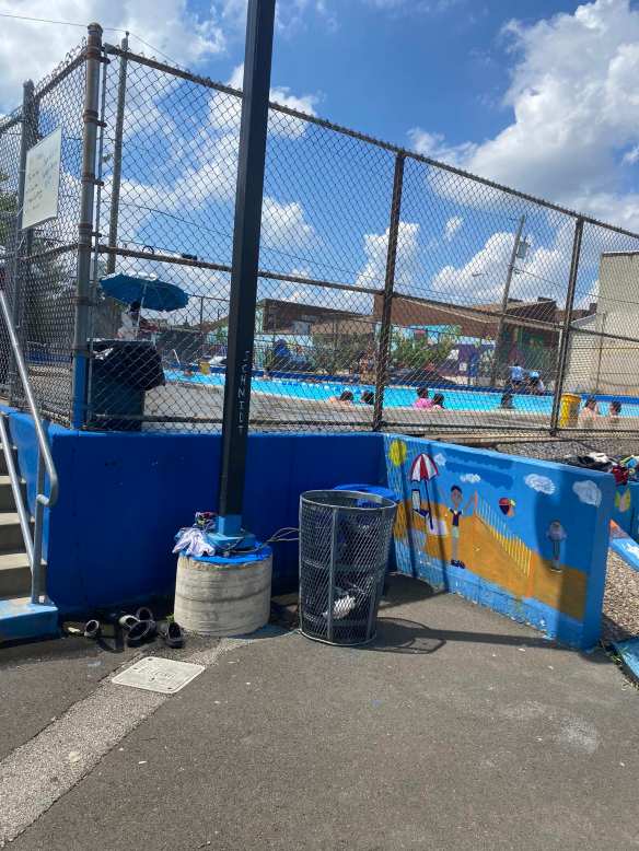 outside wall of pool where swimmers have stowed their belongings