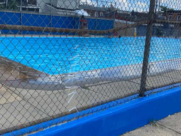 View of hole in fence alongside pool that has been repaird with zip ties