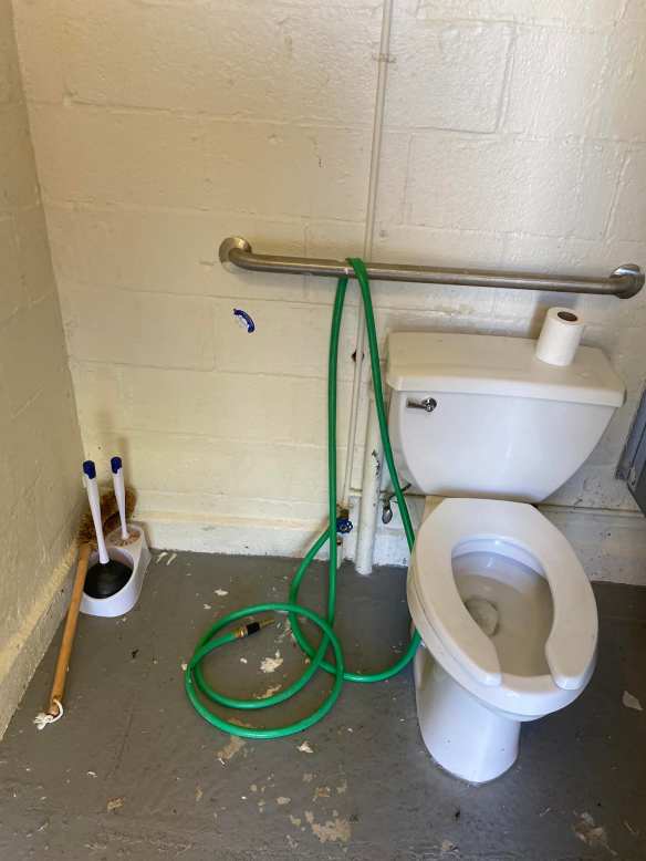 Photo of Handicap toilet in girls room with hose (and malfunctioning door)