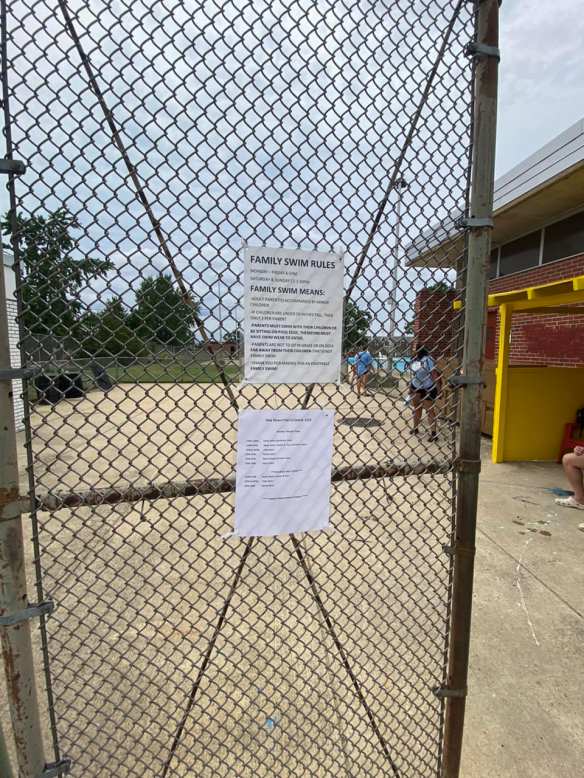 Front gate to pol deck and grassy area with Family Swim schedule posted